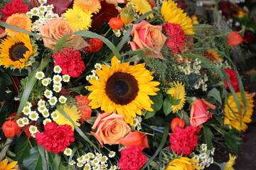 Bunte Blumen nach Beerdigung auf dem Friedhof mit Sonnenblumen  formatfüllend