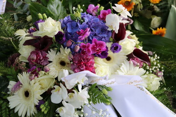 Trauerkranz mit Blumen in weiß, pink und lila nach Beerdigung auf dem Friedhof