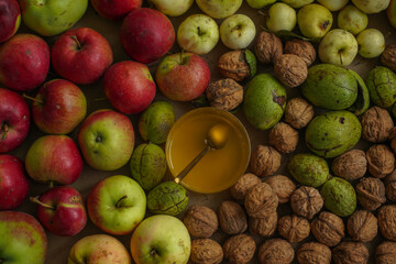a golden spoon in transparent honey on a background of fresh apples and nuts