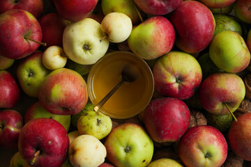 Top view, spoon in glass with honey, many fresh farm apples around
