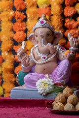 A Beautiful clay statue/Idol of an Indian god Lord Ganesha decorated with colourful Marigold garland 