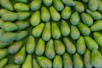 Top view a bunch of green organic avocado fruits in the market, copy space.