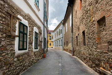 Fotobehang Narrow street in old town of Szekesfehervar, Hungary. Its cozy old-fashioned streets and buildings are popular tourist attractions © andibandi