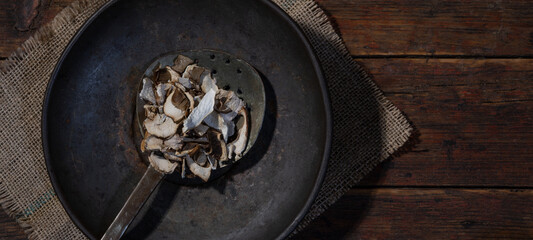 Dark food photography background - Forest mushrooms / Boletus edulis (king bolete) / penny bun / cep / porcini / mushroom on metal bowl on table, top view