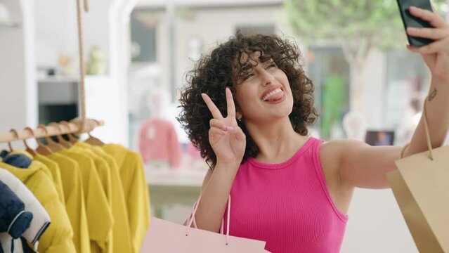 Young middle eastern woman customer smiling confident make selfie by smartphone at clothing store