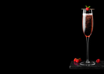 Elegant glass of pink rose champagne with raspberry on stick with fresh berries and mint leaf on...