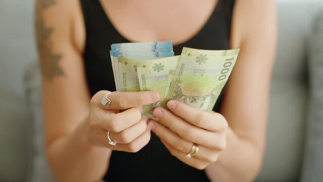 Young woman counting chile pesos banknotes at home