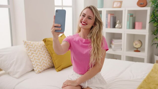 Young beautiful hispanic woman make selfie by smartphone sitting on bed at bedroom