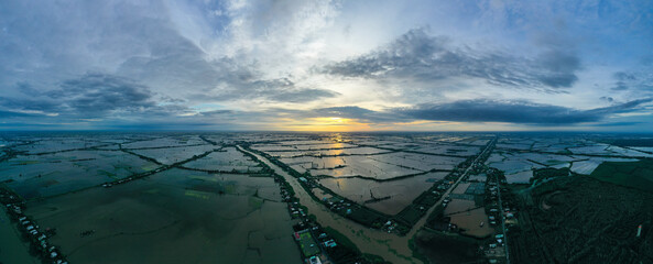 Aerial sunrise panorama view of colorful Mekong Delta over water and agricultural land in Vietnam.