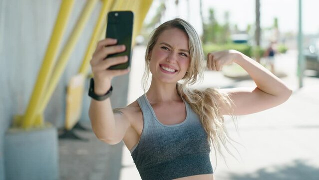 Young blonde woman wearing sportswear make selfie by smartphone at street