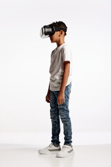 School age boy wearing casual style outfit enjoying 3D technology in virtual reality headset isolated on white background