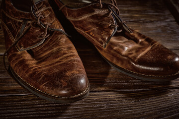 Vintage distressed leather shoes, grunge brown leather boots, rough wooden background 