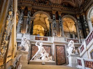 Vienna, Austria - July 6 2022: Museum of Art History, Kunsthistorisches Museum, Wien. Inside of the entrance in the art museum. Grand stairs up, with red marble, black pillars and white statues