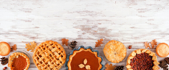 Assortment of homemade fall pies. Pumpkin, apple and pecan. Top down view bottom border on a white wood background with copy space. © Jenifoto