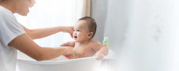 young Asian mother is Bathing with her newborn baby In Bathtub at home.Concept of newborn,baby,parenthood,motherhood,childhood,New life,maternity,love,new family member
