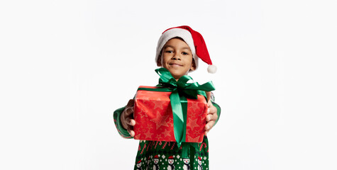 Gift for you. Happy smiling child in a knitted colorful sweater holds box in festive package. Boy rejoices at holiday, Christmas, New Year.