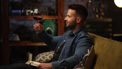 Man sitting in dark room at home drinking tasting wine, relaxing.