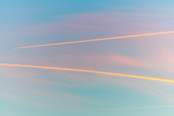 Fototapeta na wymiar Airliners in flight in a cloudy pink and orange sky in late summer.