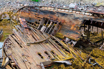 Ship cemetery in Teriberka on the coast of the Barents Sea. Old broken fishing boats in the water on the shore. Kola Peninsula, Murmansk region, Russia