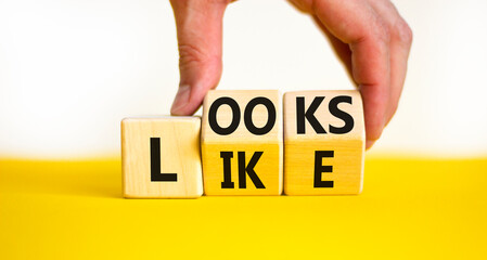 Looks like symbol. Concept words Looks like on wooden cubes. Businessman hand. Beautiful yellow table white background. Business, popular quotes and looks like concept. Copy space.