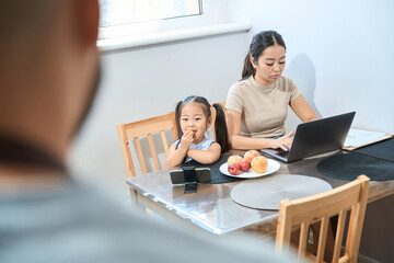 Man looks at his wife and daughter sitting at table