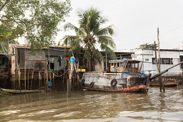 Fototapeta na wymiar Paisaje con casas y barco en el río Mekong en Vietnam.