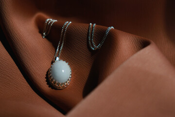 home made jewellery with breastmilk stone, silver chain on brown textil background 