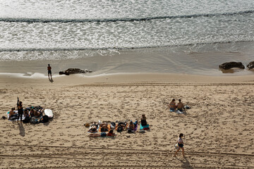 Paisaje de playa con gente tumbada tomando el sol.