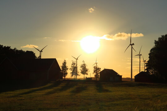 Giant sun at sunset one summer evening. Swedish countryside with wind power turbines. Near Skara, Sweden, Europe.