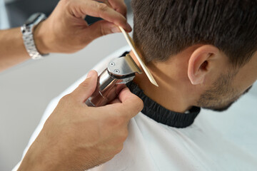 Skilled barbershop worker using proper tools while cutting guest hair