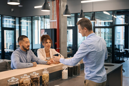 Corporate employee handing beverages to his coworkers at bar counter