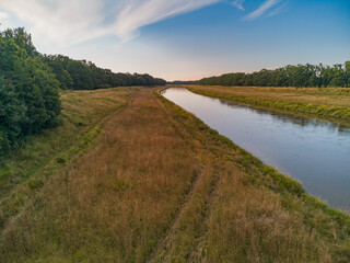 Beautiful colorful landscape of long field between forest and long Odra river