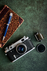 Vintage camera, old book, photographic film and pen on dark green background, top view - 533022142