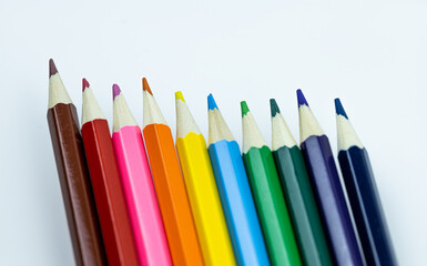 Close-up of colorful pencils arranged in a row, showcasing vibrant hues and sharp points against a white background.  Perfect for creativity and art-related projects.