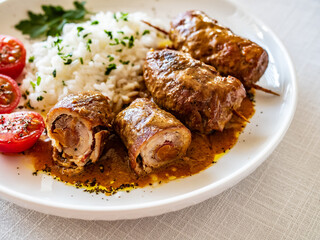 Wrapped pork served with white rice and cherry tomatoes  on white table