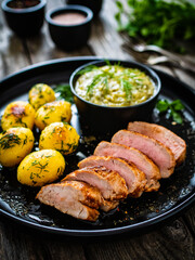 Roast pork loin with fried potatoes and cabbage on wooden table