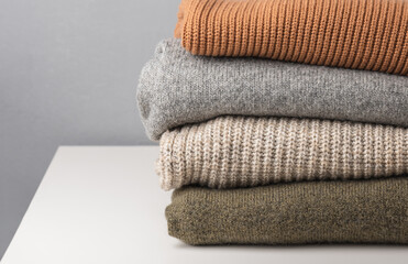 Stack of knitted wool sweaters in gray and brown colors. Warmth and comfort.