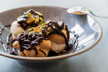 Profiterole dessert with chocolate sauce and pistachio and ice cream