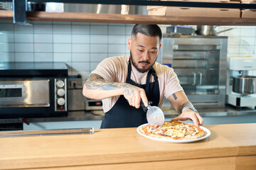 Focused cook using a pizza cutter to separate the slices