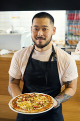 Ambitious young cook presenting a delicious handmade pizza