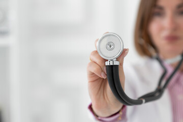 Portrait of beautiful female doctor holding stethoscope in the office of modern clinic in health...