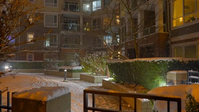 Establishing shot of modern apartment building with beautiful winter snowfall landscape at night in Vancouver, Canada, North America. Night time on December 2021. ProRes 422 HQ.
