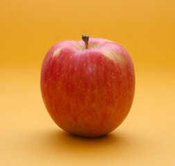 Red apple on orange background. Shallow depth of field