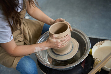 Fototapeta na wymiar Craftswoman forms a clay pot on a potter wheel