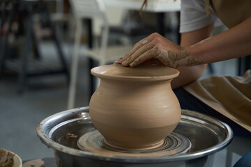 Potter works with a clay vase on a potter wheel