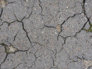 Old cracked grey asphalt surface. Cracked  asphalt texture for background. Front view with copy space.