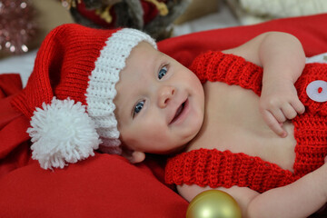 Portrait of a newborn baby in Christmas clothes and Santa hat.