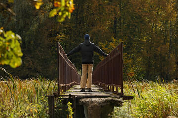 Young man in a black jacket standing on a narrow bridge. Pavel Kubarkov, i on narrow bridge and autumn nature around me. Photo was taken 20 September 2022 year, MSK time in Russia. - 533031910