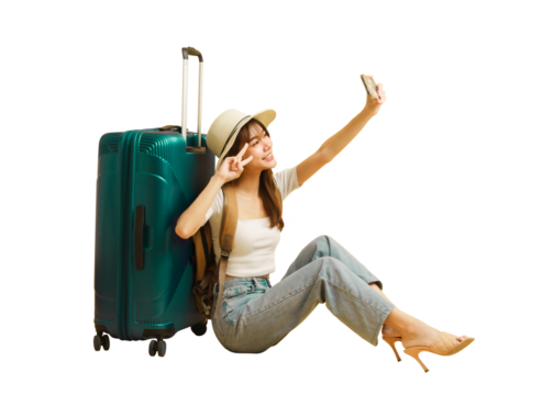 Asian beautiful woman traveler sitting nearby luggage and raised smartphone to selfies.