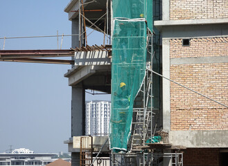 MELAKA, MALAYSIA -MAY 8, 2022: Temporary staircase made of steel and scaffolding that connects floor by floor. Used by construction workers. This ladder is wrapped with safety netting.